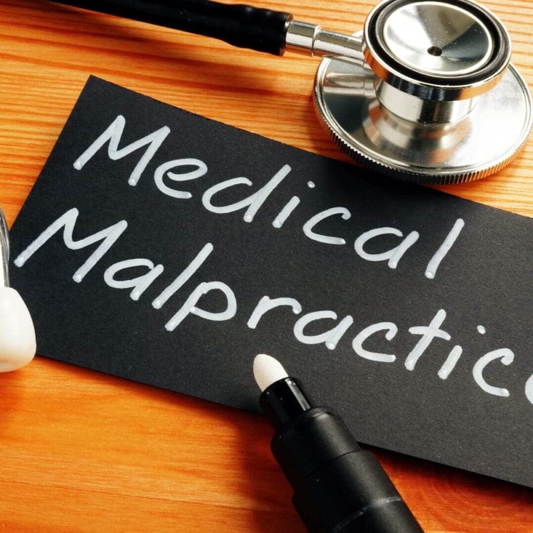 Medical Malpractice written on it, placed on a wooden surface.